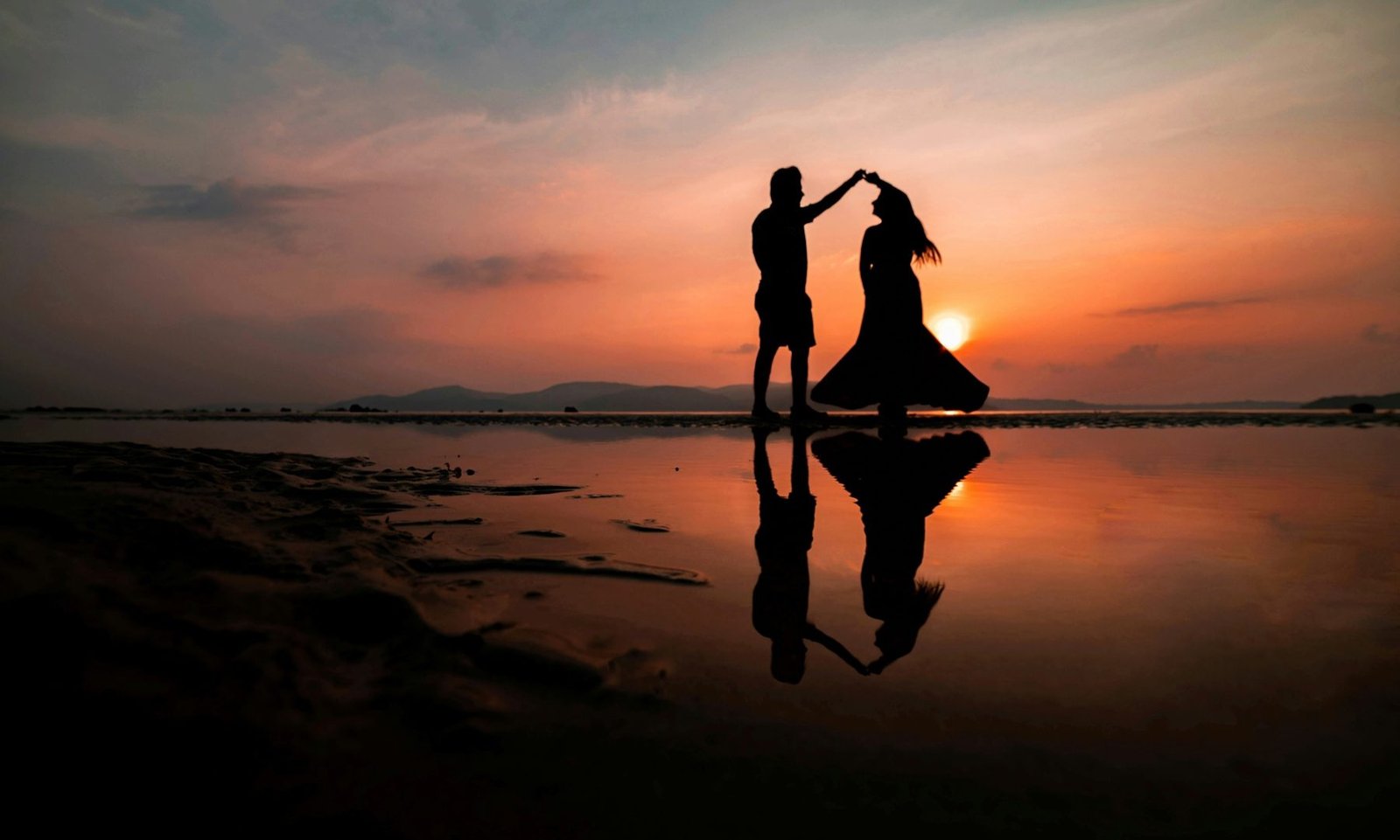 Silueta de una pareja bailando frente al mar al atardecer