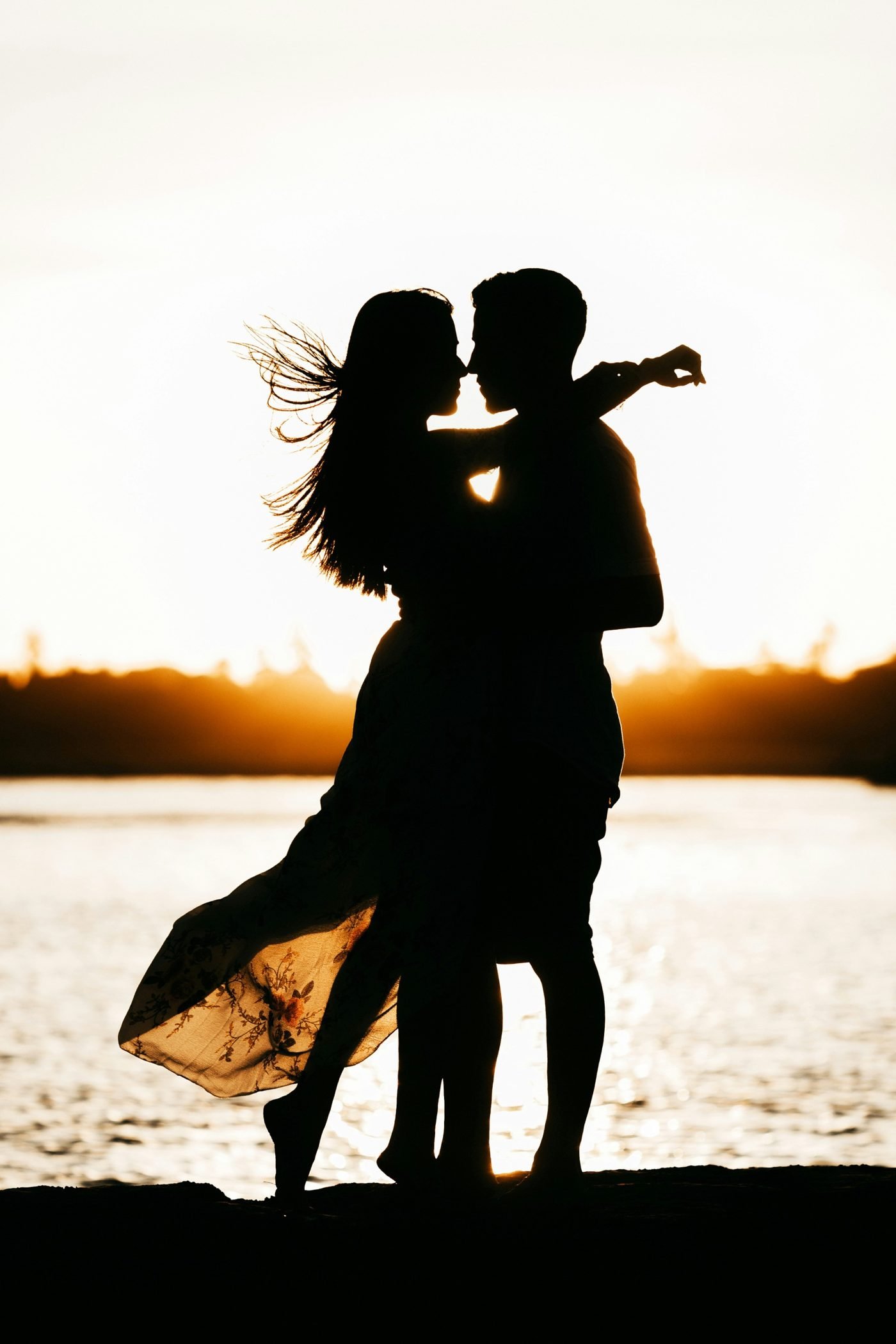 Silueta de una pareja abrazada frente al lago al atardecer